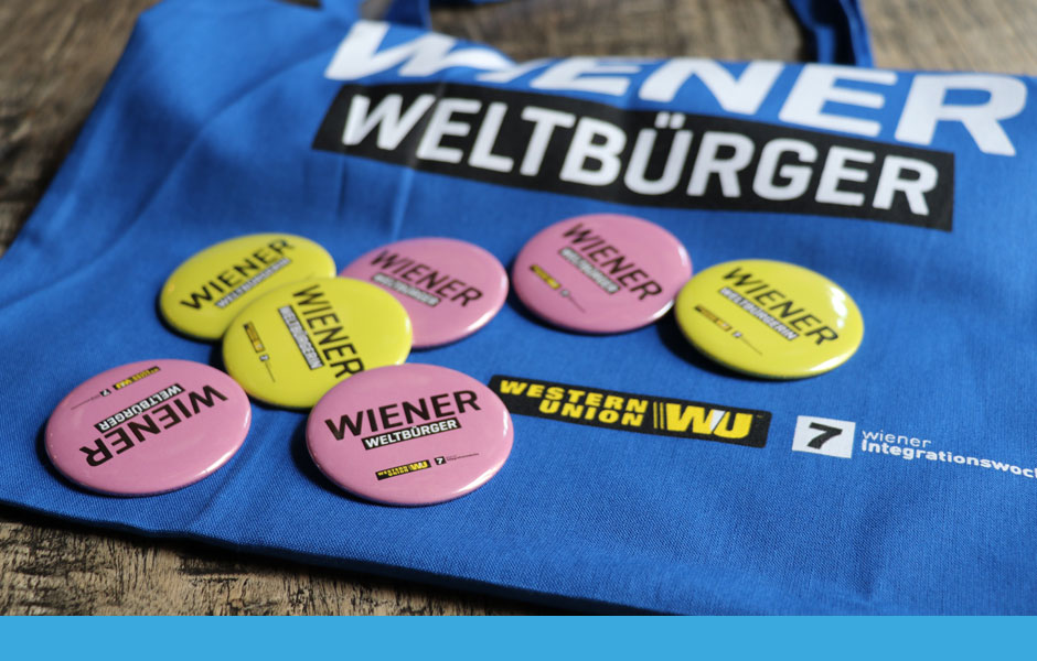 Die Weltoffenheit nach außen tragen: Wiener Weltbürgerin in verschiedenen Sprachen als Buttons und Tragtaschen.